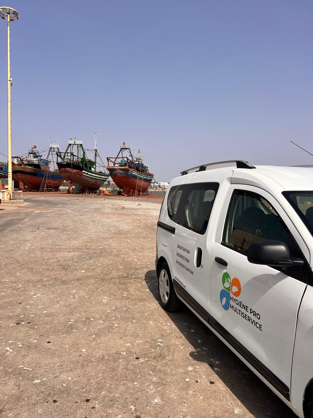 Véhicule d'intervention Hygiène Pro Multiservice garé devant les bateaux du port de pêche d'Essaouira