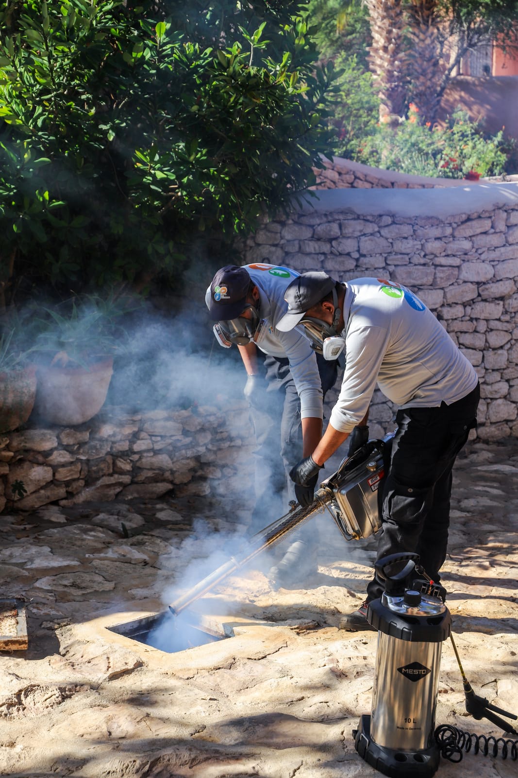 Équipe HPS en pleine intervention de désinsectisation d'un regard, masques et nébuliseur thermique