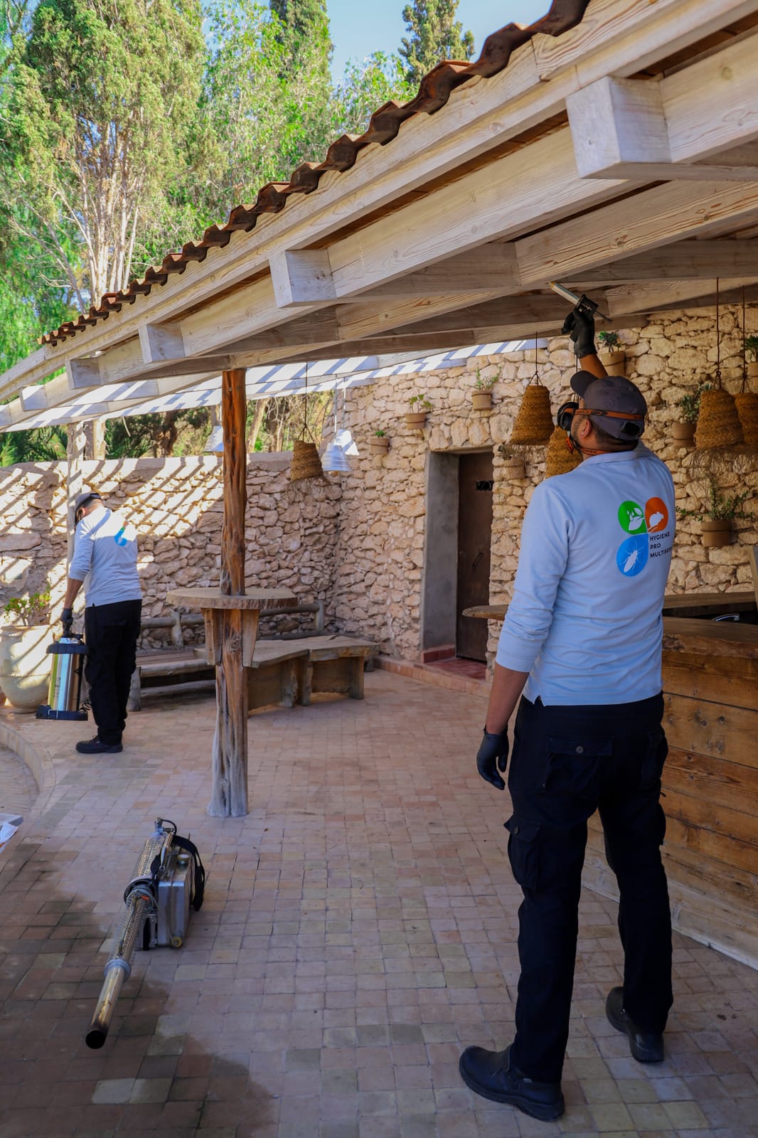 Technicien HPS appliquant un traitement préventif sur la charpente en bois d'une pergola